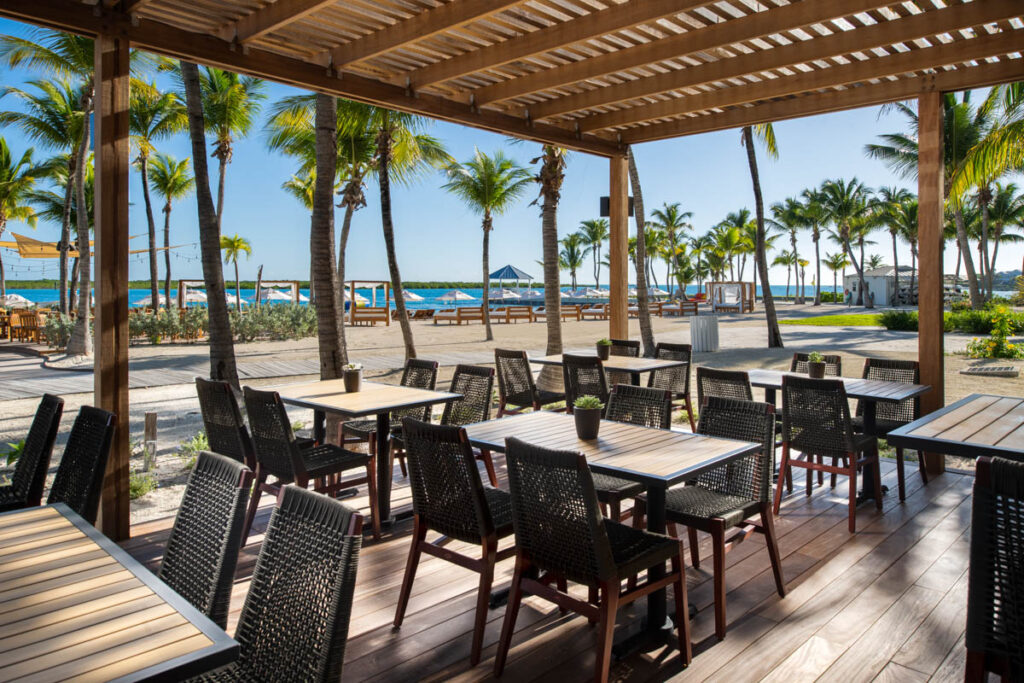 Outdoor open air seating at Cafe Agave with view of Blue Haven's private beach in the distance.